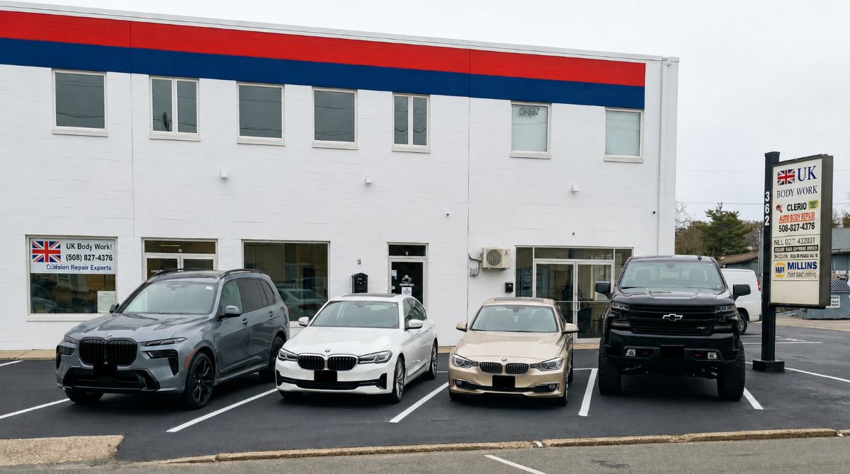 Front view of UK Body Work auto body and collision repair shop in Hyannis Massachusetts with repaired luxury vehicles parked outside